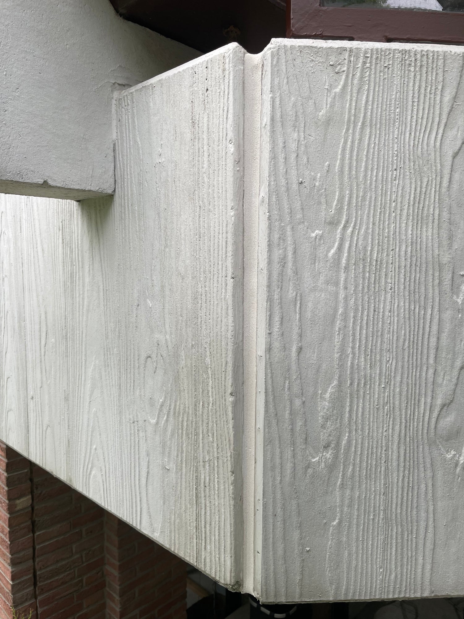 Eine unsichtbare Dehnungsfuge zwischen zwei Balkonbrüstungen. Die Brüstungen sind Fertigbetonteile in weiß, die Silikonfuge ist besandet und so an die Farbe der Brüstung angepasst sodass man sie fast nicht erkennt.