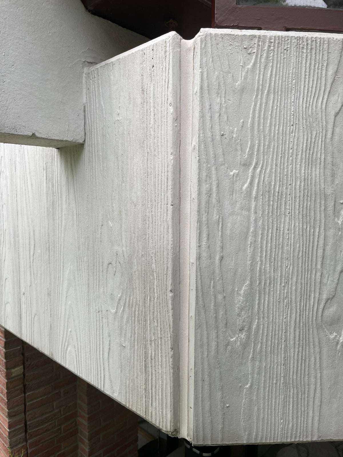 Eine unsichtbare Dehnungsfuge zwischen zwei Balkonbrüstungen. Die Brüstungen sind Fertigbetonteile in weiß, die Silikonfuge ist besandet und so an die Farbe der Brüstung angepasst sodass man sie fast nicht erkennt.