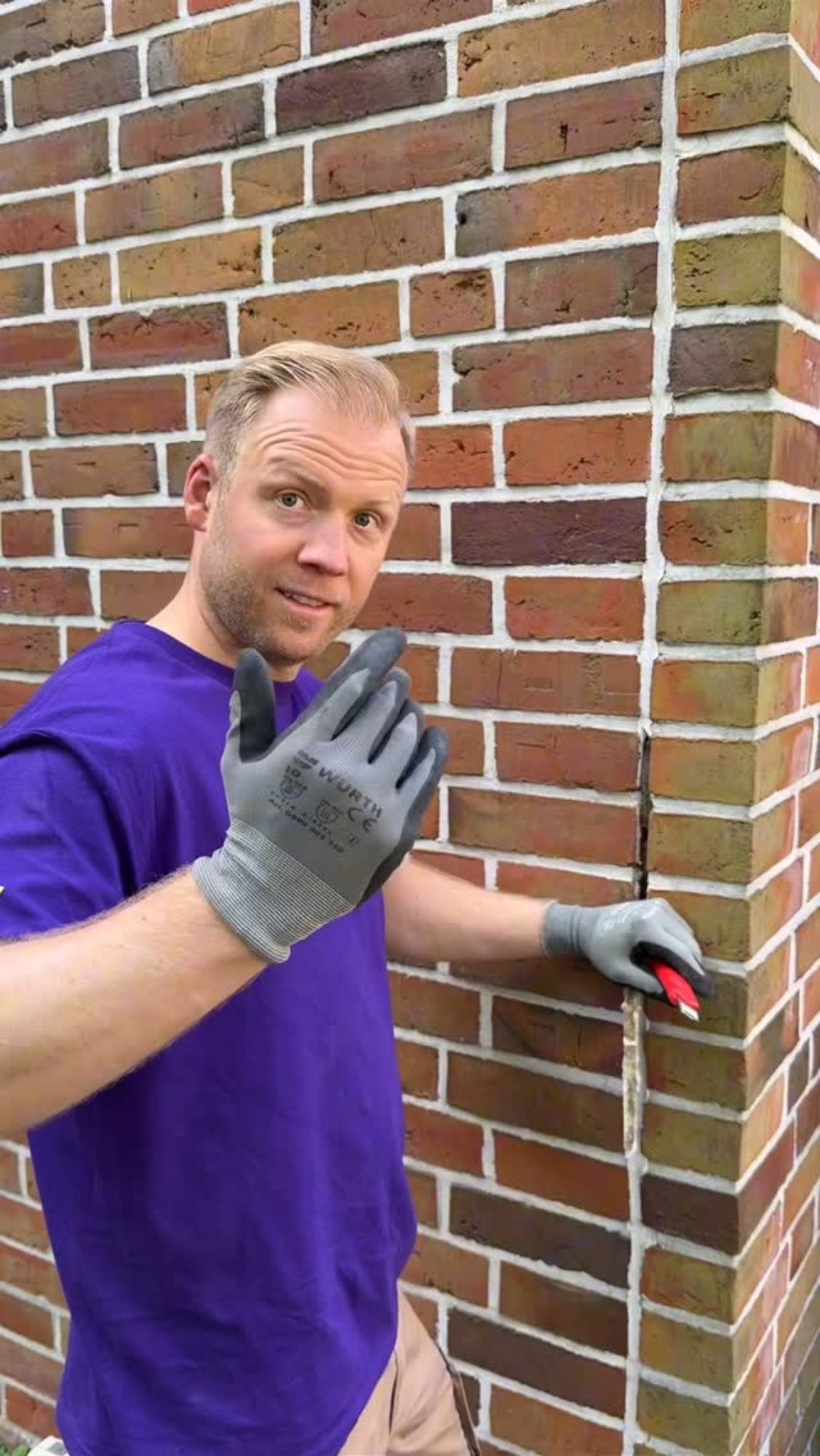 Ein Mitarbeiter von Fugentech steht vor einer kaputten Dehnungsfuge an einer Klinkermauer